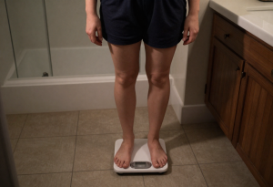 why you feel heavier at night - Person standing on a scale at night noticing weight change