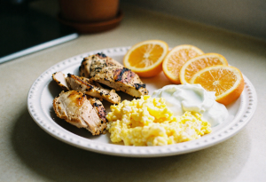 Healthy breakfast plate with eggs, fruit, and yogurt, illustrating protein and fiber to prevent feeling hungry