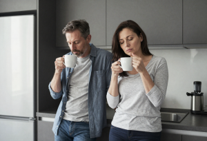 Middle-aged couple looking tired while making coffee in the morning after drinking
