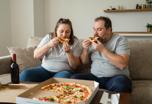 Middle-aged couple eating junk food at home, showing lifestyle factors affecting sex drive