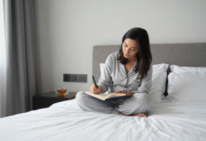 improve your mental health - adult writing in a journal at a bright desk, with a cup of tea