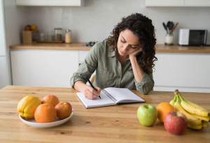 Nutrition Basics - Adult writing a meal plan surrounded by healthy foods, practicing balanced nutrition habits