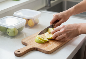 Adult chopping fresh fruit in a modern kitchen as part of a tiny daily habit