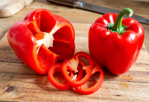 Fresh red bell peppers sliced on a wooden surface, showing vibrant color and glossy texture for nutrition and immune health