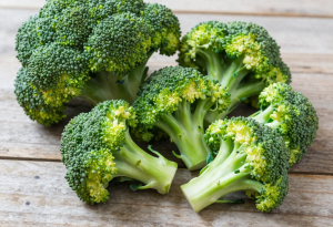 Fresh green broccoli florets on a wooden table, highlighting texture and vibrant color for nutrition and health