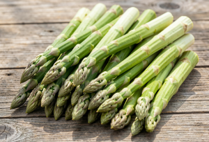 Fresh green asparagus spears on a wooden surface, highlighting vibrant color and texture for digestion and hormone health