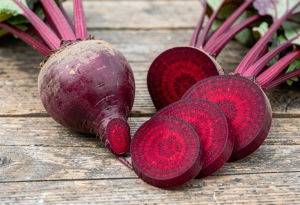 healthiest vegetables - Fresh red beets whole and sliced on a wooden surface, showing vibrant color and interior rings for heart and circulation health