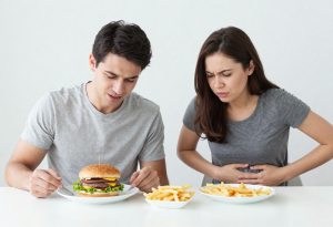 “Person with hand on stomach feeling discomfort after eating fast food, representing digestive issues”