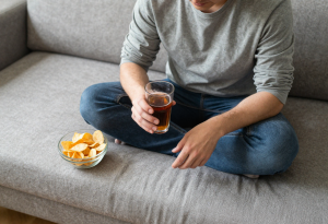 Person drinking a soft drink with chips nearby to illustrate foods to avoid after overeating