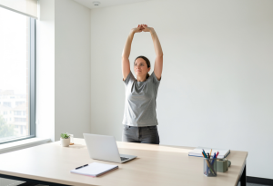 Adult standing and stretching at a desk as a small daily habit for improved health and circulation.