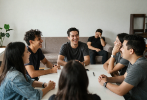 person sitting on a couch looking tired and disengaged while others socialize, illustrating early signs of burnout