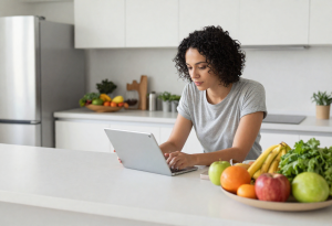 Person reading health information at a kitchen counter with fresh produce, representing learning about managing sugar cravings and digestive health.
