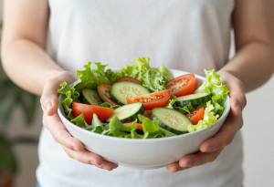 Person holding a bowl of fresh salad, illustrating foods that support healthy digestion