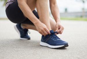 Person putting on running shoes before a walk, representing healthy daily habits that support digestion