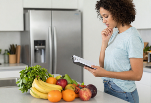 Person thoughtfully selecting fruits and vegetables at a kitchen counter, illustrating common questions about healthy and nutritious foods