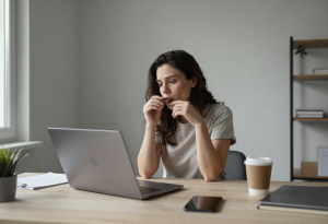 Tired woman at desk reaching for chocolate during an afternoon energy slump, representing sugar cravings.