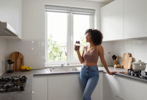 plant protein vs whey protein - Person preparing a midday protein shake with whey and plant protein alongside a bowl of oats and fruit.