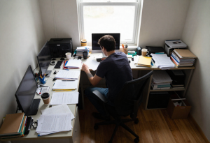 Person sitting at a cluttered home office desk, showing how a messy workspace can affect focus.