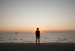 Person standing on a beach at sunset, reflecting and resetting their mind after a busy day.