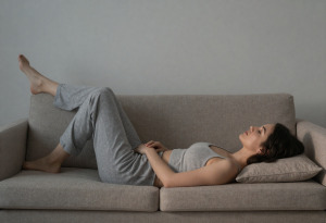 Woman lying on her back with legs elevated against a wall, showing a simple evening habit to reduce bloating and fluid retention