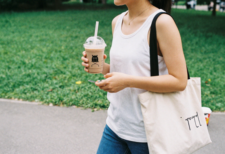 Woman walking to work with a creamy takeaway coffee, illustrating hidden calories in everyday routines