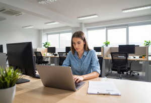 Person sitting upright at a desk, shoulders back and core engaged, practicing proper posture to prevent headaches