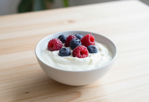 Bowl of plain Greek yogurt topped with fresh mixed berries, a healthy evening snack that supports digestion and sleep.