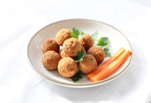 Three golden mini chicken balls on a plate with carrot sticks, ready-to-eat protein snack