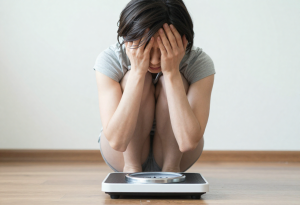 Person checking weight on a scale while tracking calories for health