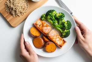 what is glucose - Hands plating a healthy balanced meal with protein, vegetables, and grains to maintain stable blood sugar