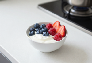 Small glass jar filled with low-fat yogurt topped with blueberries, strawberries, and raspberries, healthy snack