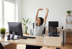 Woman stretching at a desk with a glass of water nearby, representing sodium’s role in hydration and muscle function.