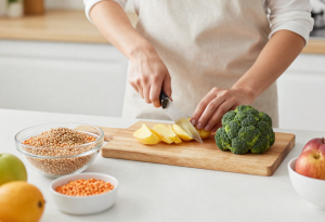 Person preparing healthy carbohydrate sources like potatoes, broccoli, pasta, lentils, and fruit
