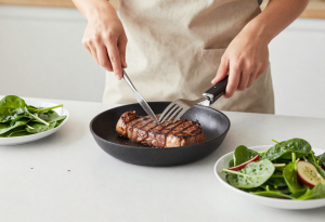 Family/friend preparing or enjoying a meal with grilled chicken and a spinach salad, showing sources of dietary iron