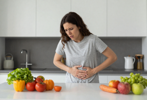 Woman holding her side and looking concerned, with liver-friendly foods nearby, illustrating early signs that the liver may need support