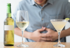 Young adult holding stomach with mild bloating after drinking alcohol.