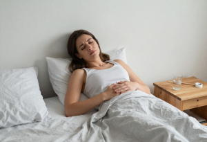 Young adult waking up with mild bloating after drinking alcohol the night before.